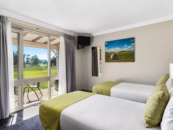 a bedroom with curtains that open up to scenic nature views at Quality Inn Carriage House