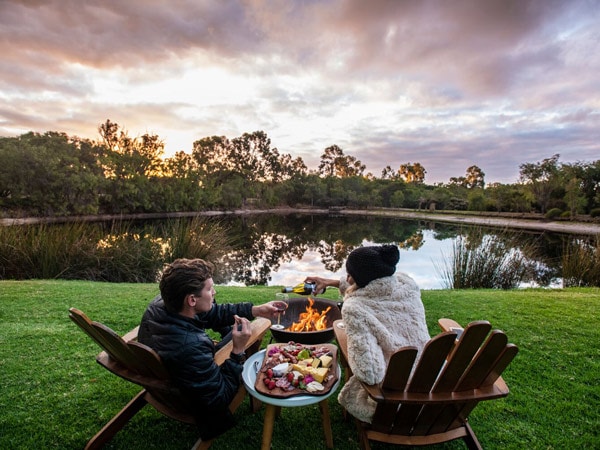 A couple enjoy nibbles and wine by the fire. (Image: Forest Rise Chalets and Lodge)