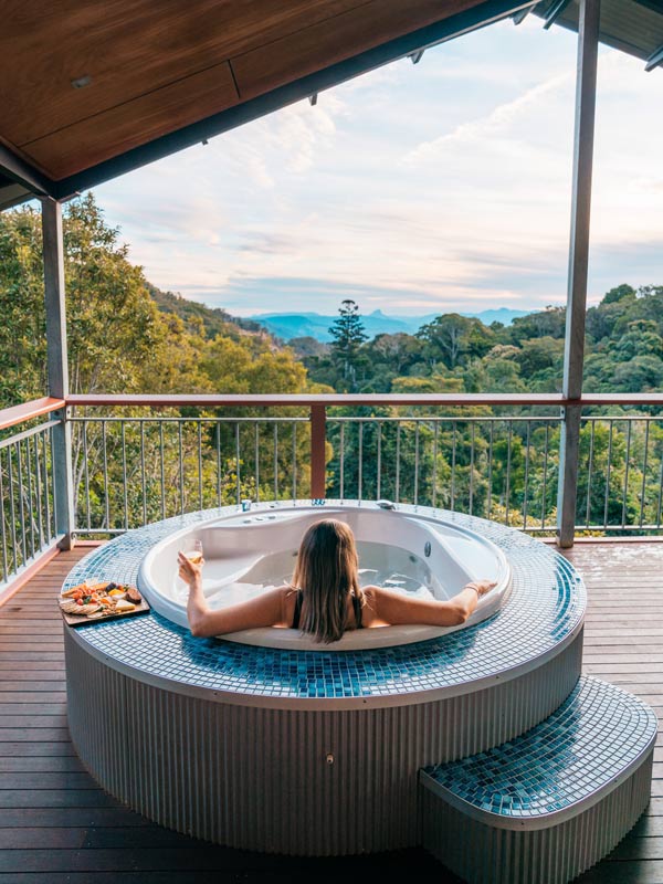 Woman relaxing in a spa on the balcony of a Villa at O'Reilly's Rainforest Retreat. (Image: Tourism and Events Queensland)