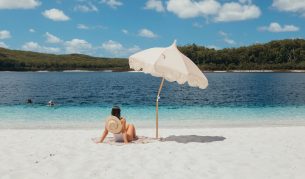 A woman relaxes on the white sand at Lake McKenzie(Image: Tourism and Events Queensland)