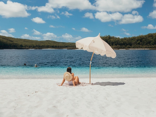 Μια γυναίκα χαλαρώνει στη λευκή άμμο στη λίμνη McKenzie (Εικόνα: Τουρισμός και εκδηλώσεις Κουίνσλαντ)