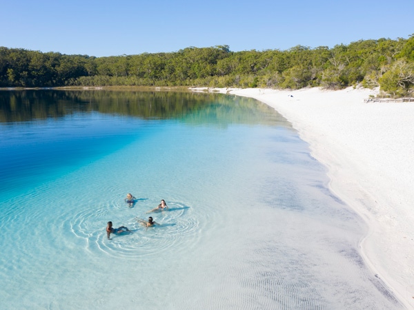 A group sit in the water at Lake McKenzie. (Image: Tourism and Events Queensland)