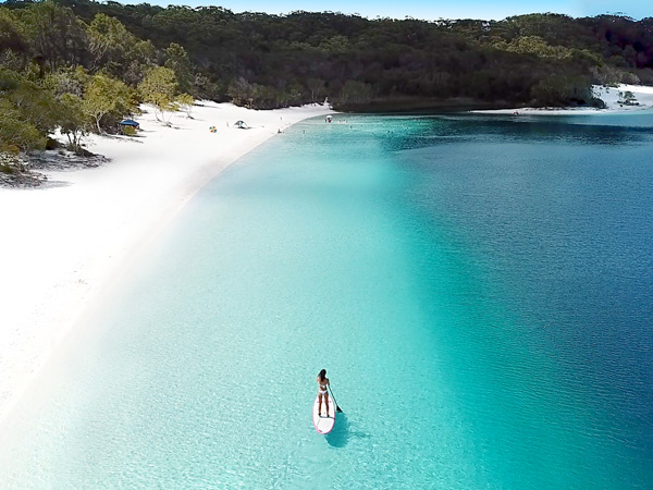 A woman paddle boarding on Lake Mckenzie. (Image: Tourism and Events Queensland)