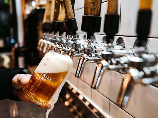 an overflowing glass of beer on tap at Three Tails Brewery, Mudgee