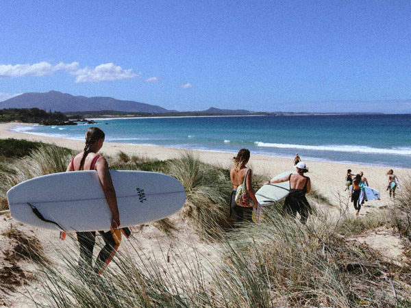 surfers holding their surfboards ready to hit the waves at Bermagui, Camel Rock Surf School