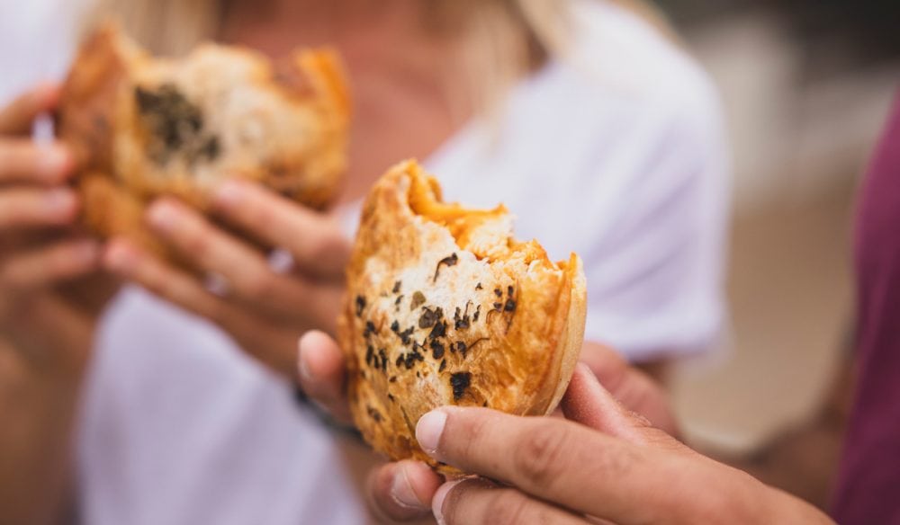 Couple enjoying pies from The Upper Crust pie shop, Collaroy (Image: Destination NSW)
