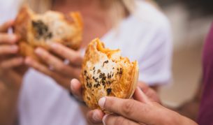 Couple enjoying pies from The Upper Crust pie shop, Collaroy (Image: Destination NSW)