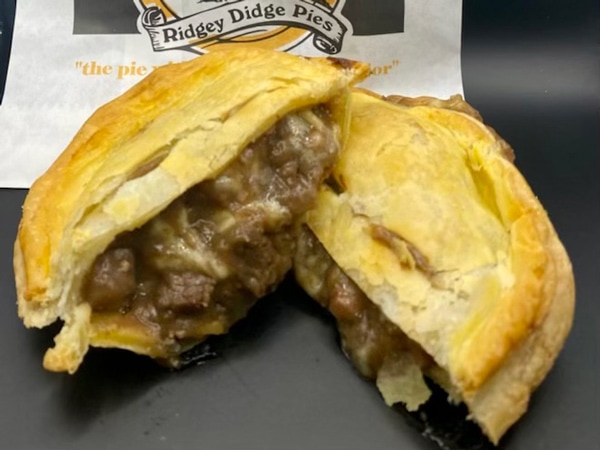 A meat pie on top of paper bag that says Ridgey Didge Pies.
