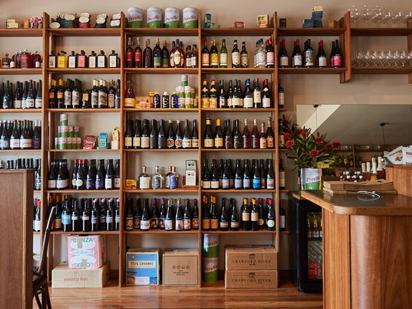 a stack of wine bottles and drinks on display at Bar Superette, Merimbula