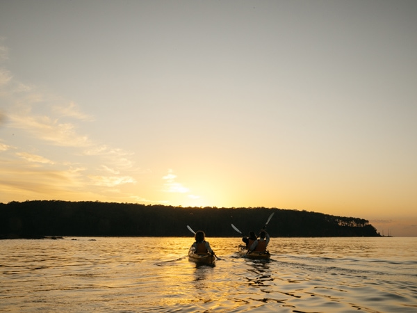 two people paddling along Batemans Bay during sunset