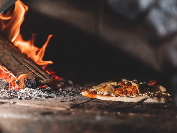 Wood-fired pizza cooking in the oven.