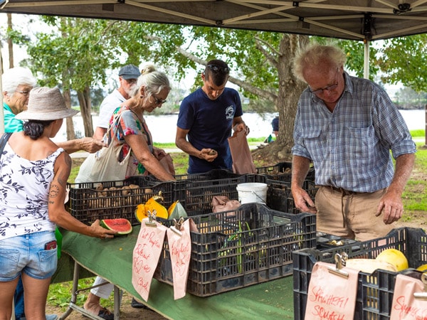 Μια μικρή ομάδα ανθρώπων που αγοράζουν προϊόντα σε έναν πάγκο στην αγορά Sage στο Batemans Bay, NSW, Αυστραλία