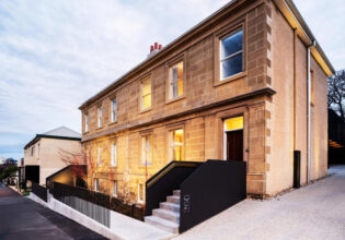 The house is made of stone and has a black railing.