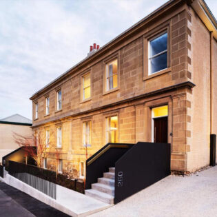 The house is made of stone and has a black railing.