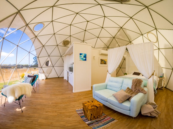 A bed inside a dome with a table and chairs.