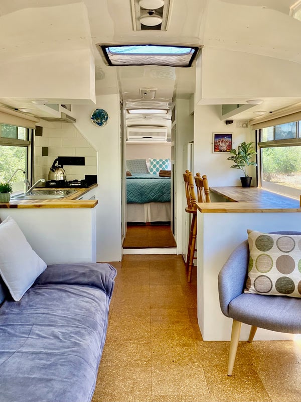 The indoors of a caravan with a little kitchen, bed, and living area.