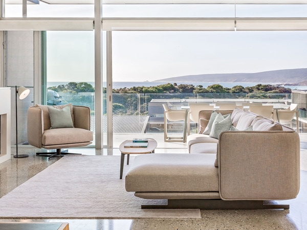 An interior with couches and a balcony with a view on the ocean.