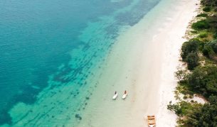 Aerial shot of two paddleboarders next to wooden row boat.