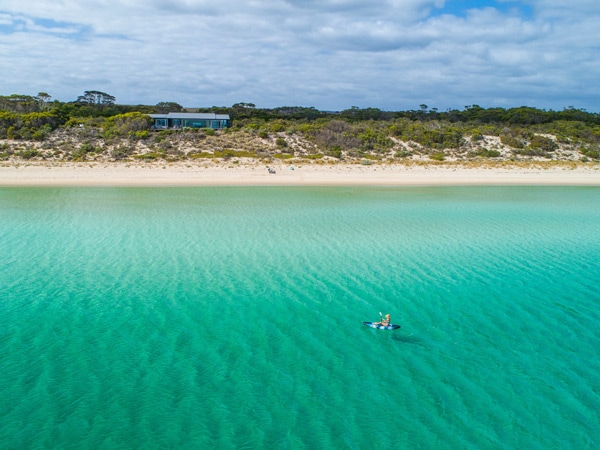 Person kayaking on Brown Beach with One Kangaroo Island in the background.