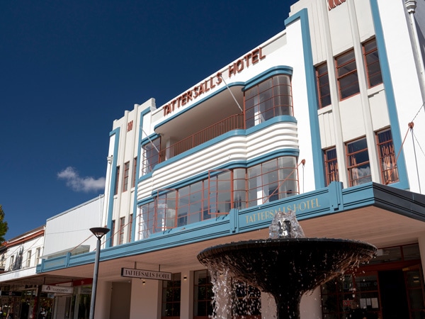 An historical facade of a hotel painted in white under a blue sky.