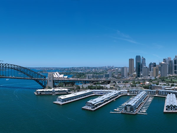 Piers on the water with a bridge and a city.