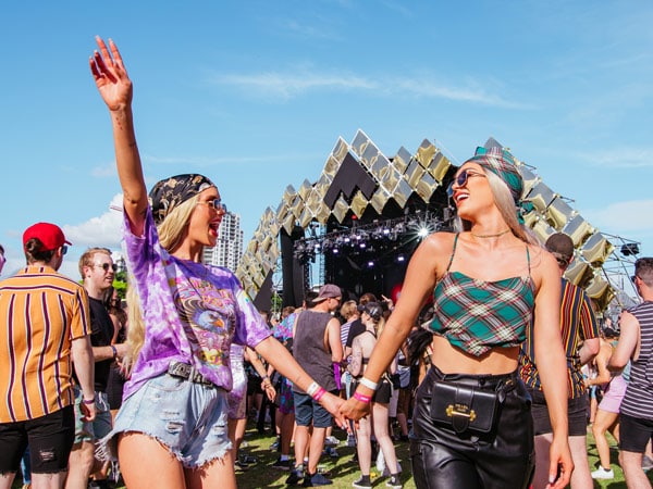 Two women holding hands at Wildlands festival.