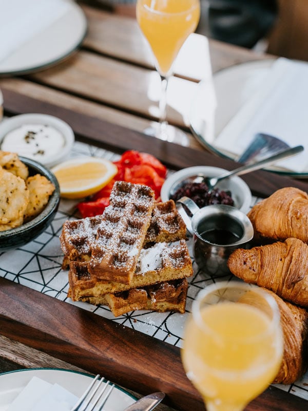 Waffles with croissants and juice on a table.
