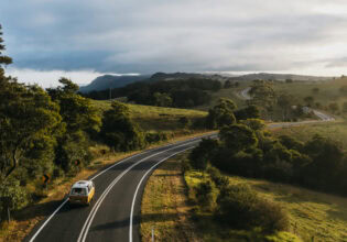 Yellow campervan driving down country roads in Bellingen
