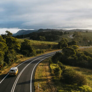 Yellow campervan driving down country roads in Bellingen