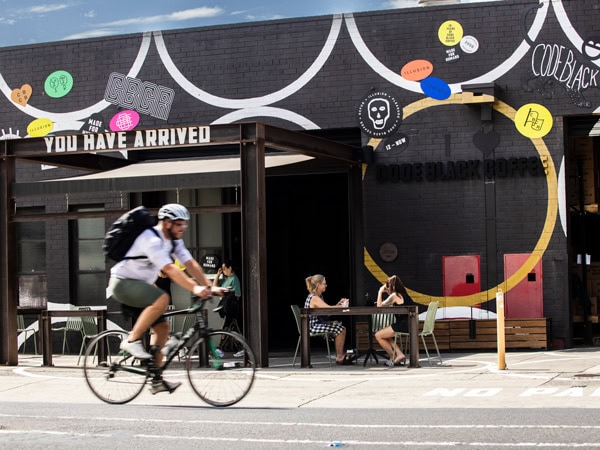 a man biking in front of Code Black cafe in Brunswick