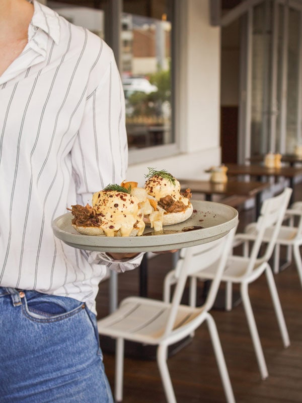 Waiter serves breakfast on a plate at Convoy in Melbourne