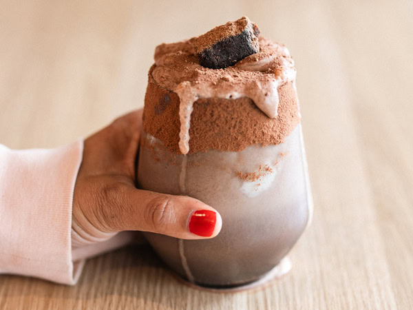 a hand holding a glass of iced milo at Lankan Tucker in Brunswick West