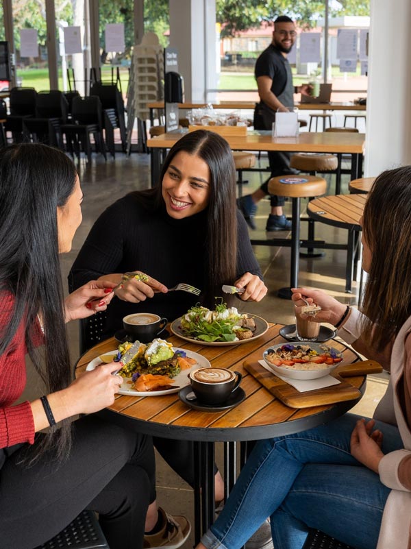 Three girls brunching and smiling at one of the cafes in Melbourne