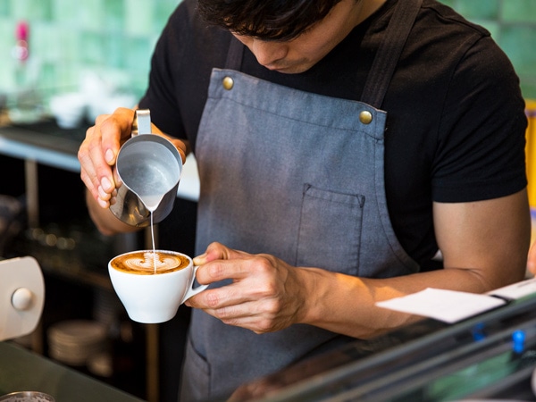 A man pouring coffee in a cup.