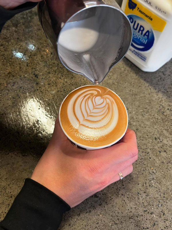 pouring milk over a cup of coffee at Two Folk Espresso, Hobart