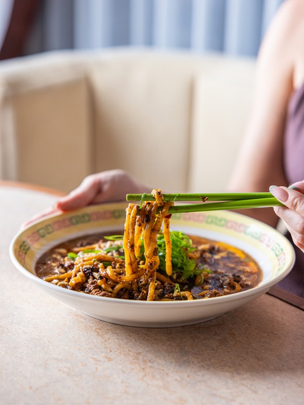 pulling noodles from a bowl with chopsticks at Casa Chow, Brisbane