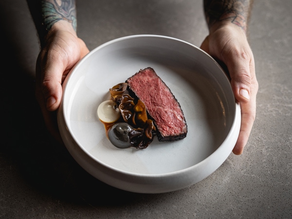 a hand holding a plate of meat at Exhibition restaurant, Brisbane