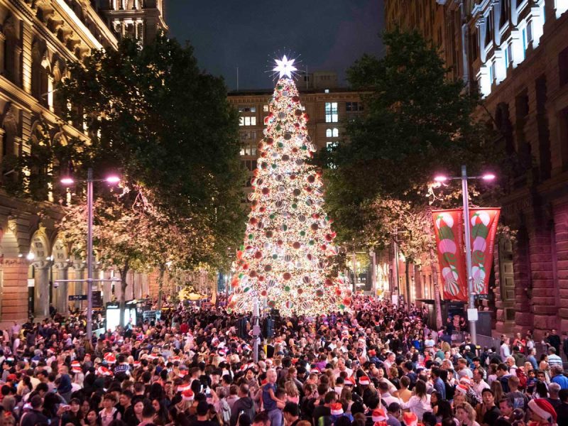 crowds surrounding a huge Christmas tree display with bright and colourful lights