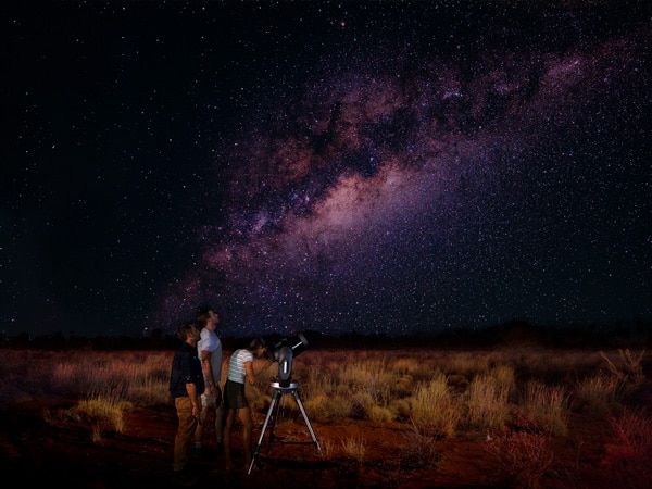 tiga orang melihat bintang di malam hari di Uluru