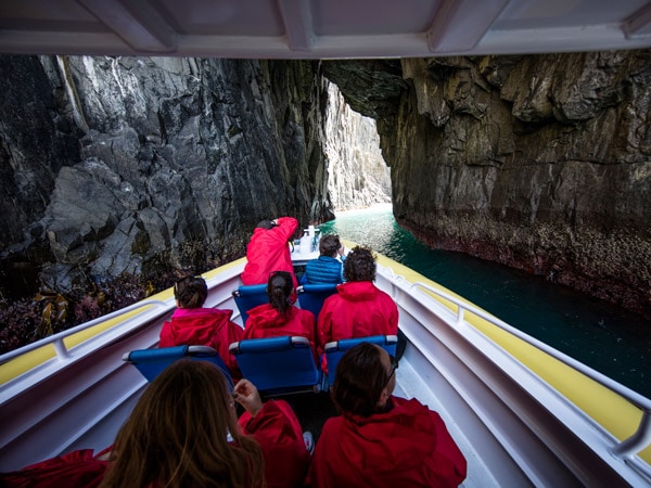 sekelompok wisatawan di kapal pesiar memasuki gua laut