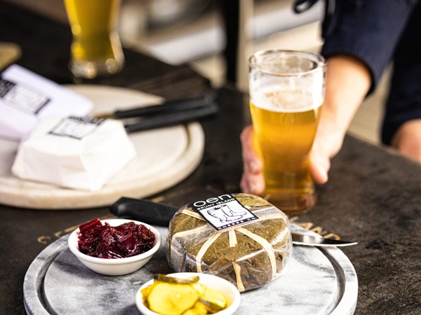 a glass of beer and artisan cheese on the table