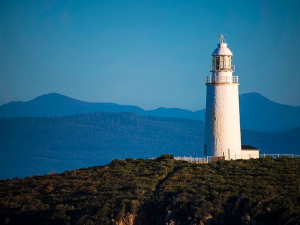 a tall lighthouse with a mountain backdrop