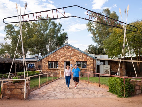 a couple posing in front of the entry point at Curtin Springs Wayside Inn