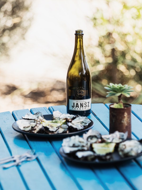 a bottle of Jansz Tasmania wine with two plates of fresh oysters