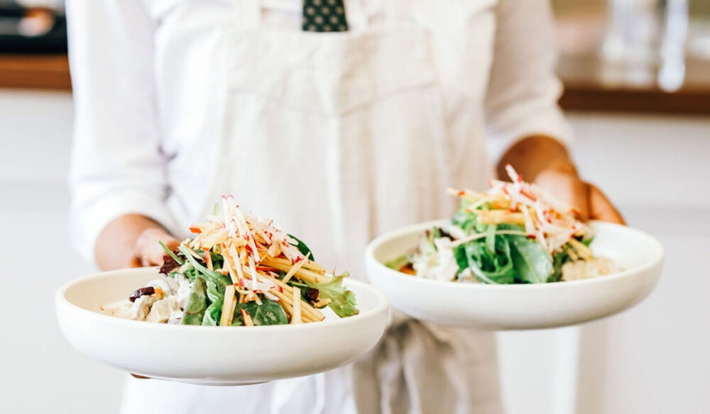 a person in white holding two plates of food at Plantation Cafe, Bowral