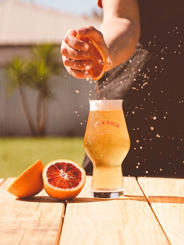 a bartender squeezing citrus fruit into a cold brew