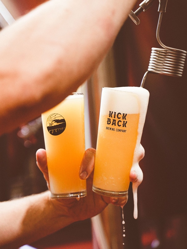 a bartender filling two glasses with tap beer