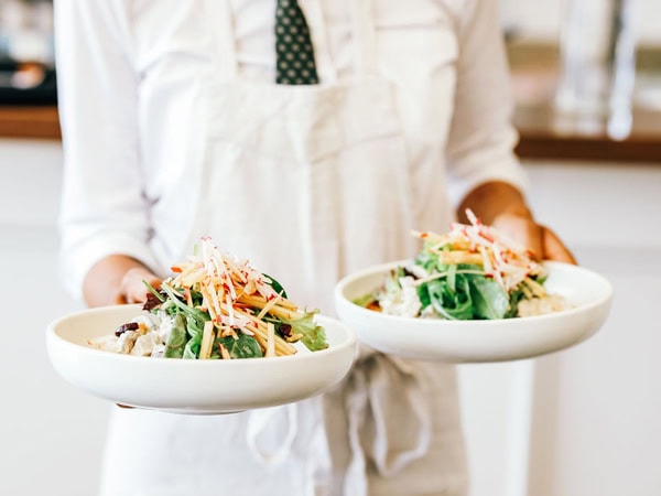 a person in white holding two plates of food at Plantation Cafe