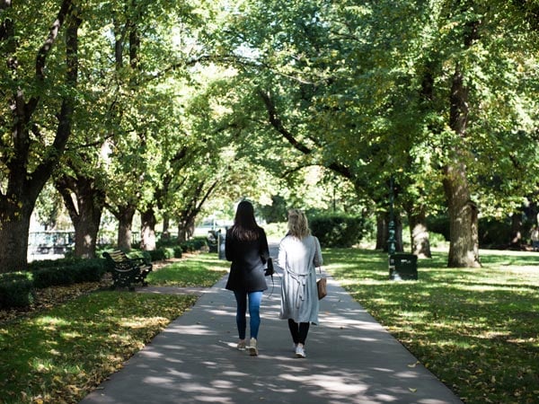 two women walking under the shade of trees in Bendigo Rosalind Park