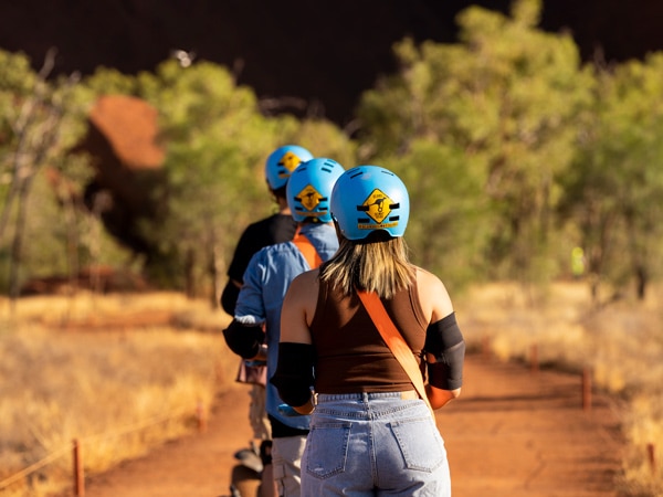 sekelompok wisatawan yang mengenakan helm selama Uluru Segway Tour